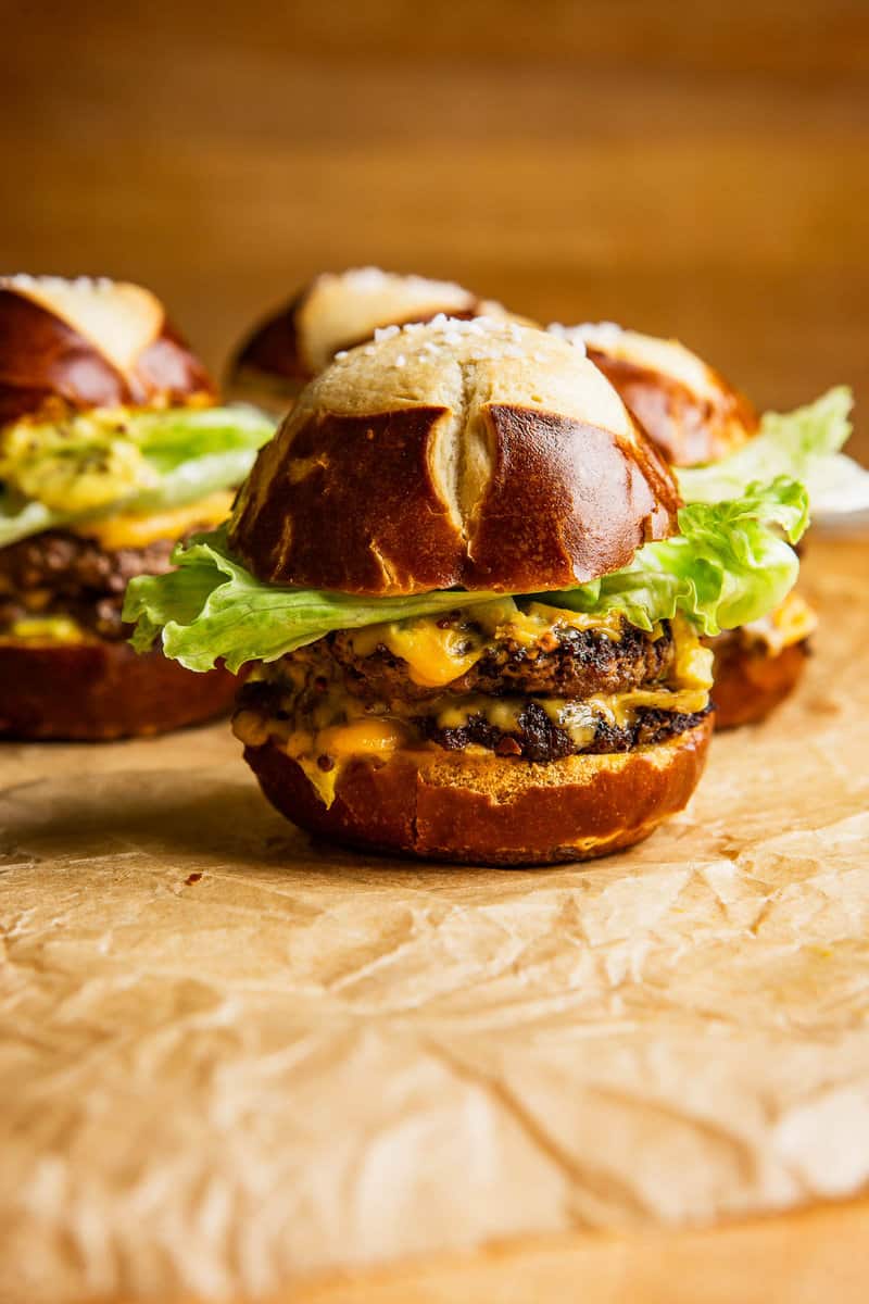 beef slider on pretzel roll set on a brown piece of parchment paper