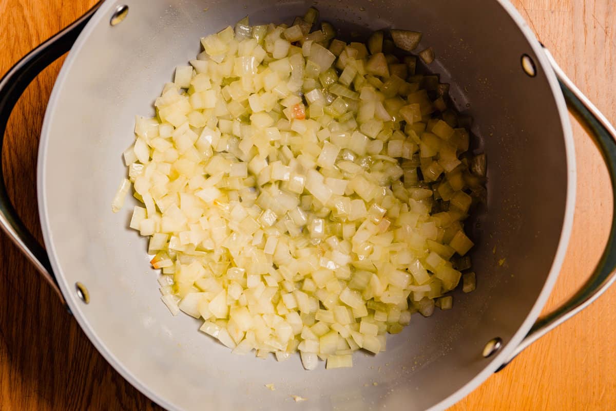 Diced onions sautéing in a large gray pot.