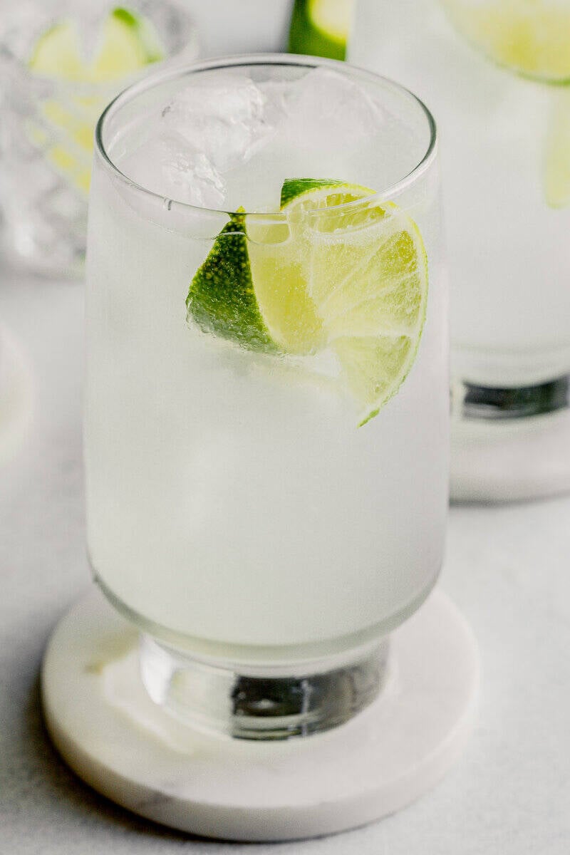 3-Ingredient Gin Rickey cocktail in a tall collins glass filled with ice and 2 lime wedges.
