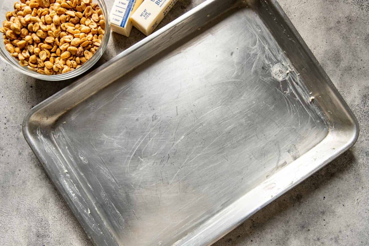 Greased baking sheet set on a counter in preparation for peanut brittle.