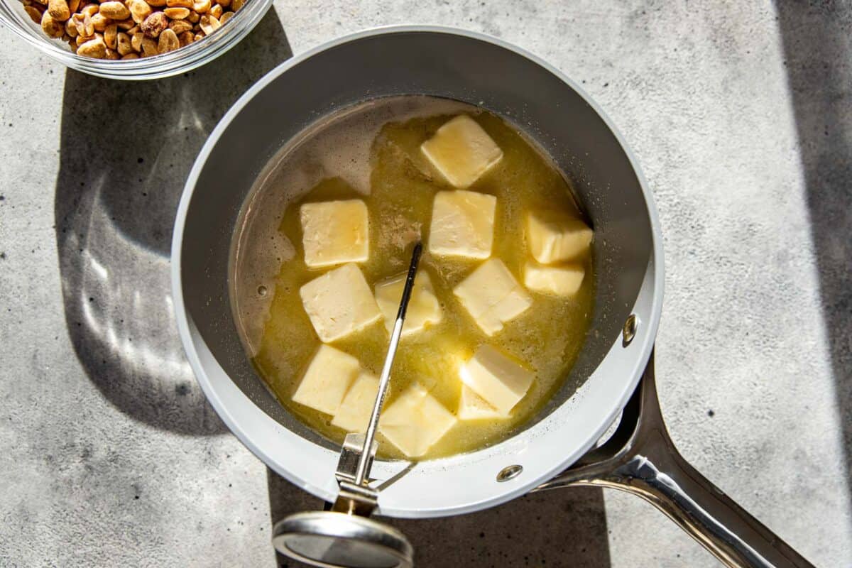 Sugar syrup and butter for peanut brittle cooking a saucepan with a candy thermometer.
