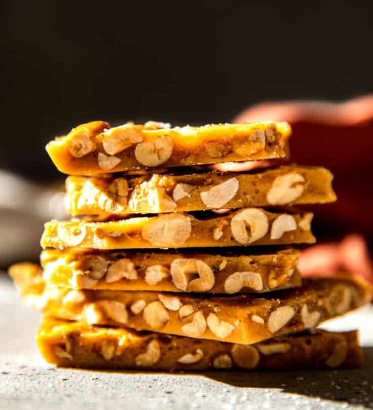 Stacked pieces of old fashioned peanut brittle showing the peanuts and crisp brittle.