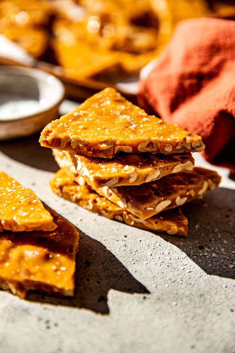 Stacked pieces of old fashioned peanut brittle showing the peanuts and crisp brittle.