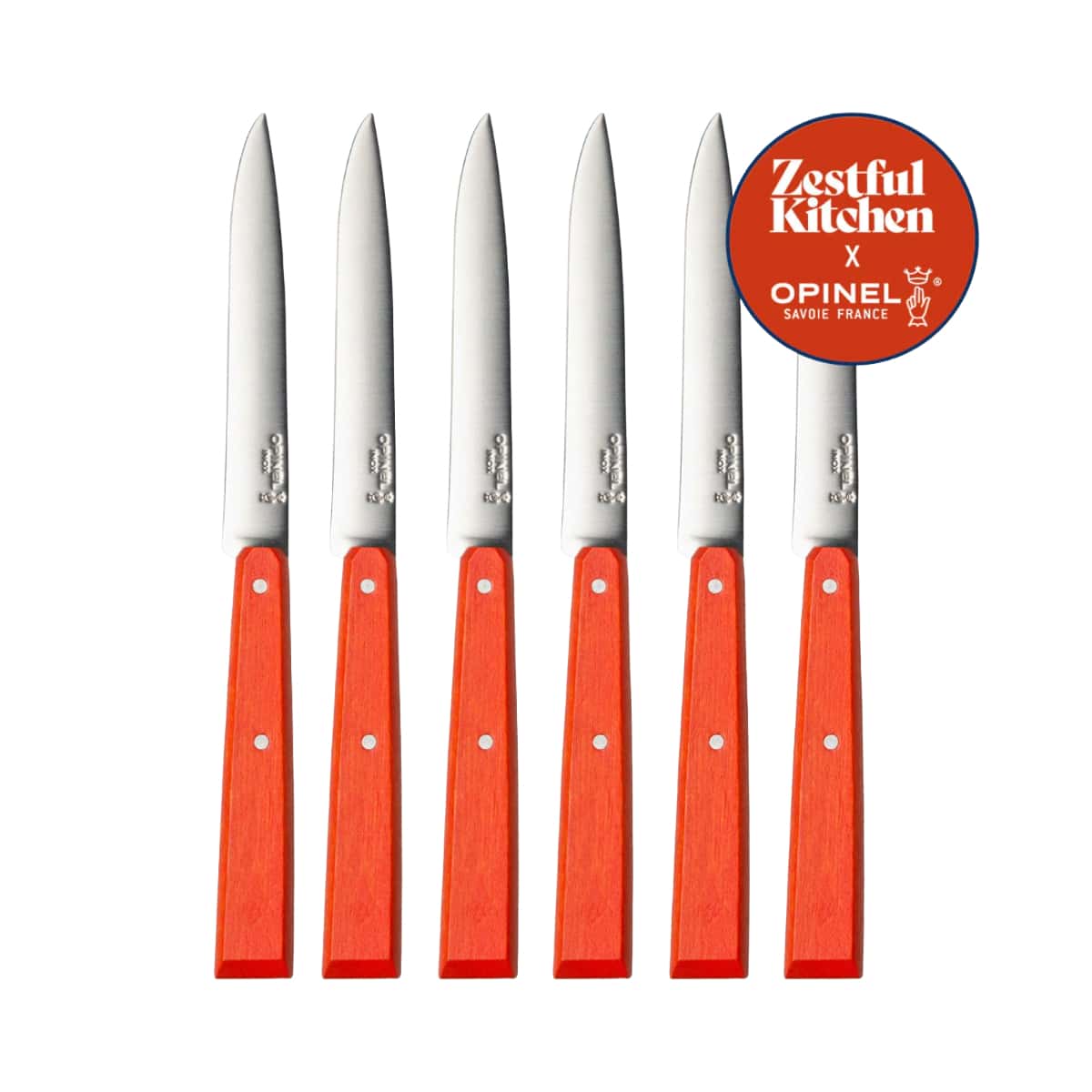 orange-handled steak knives on a white background with a branded Zestful Kitchen sticker