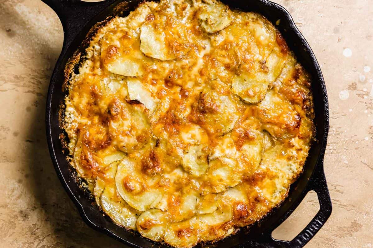 cheesy gruyere potato au gratin in a cast-iron skillet after foil is removed and baked again so the top is bubbly and golden brown.
