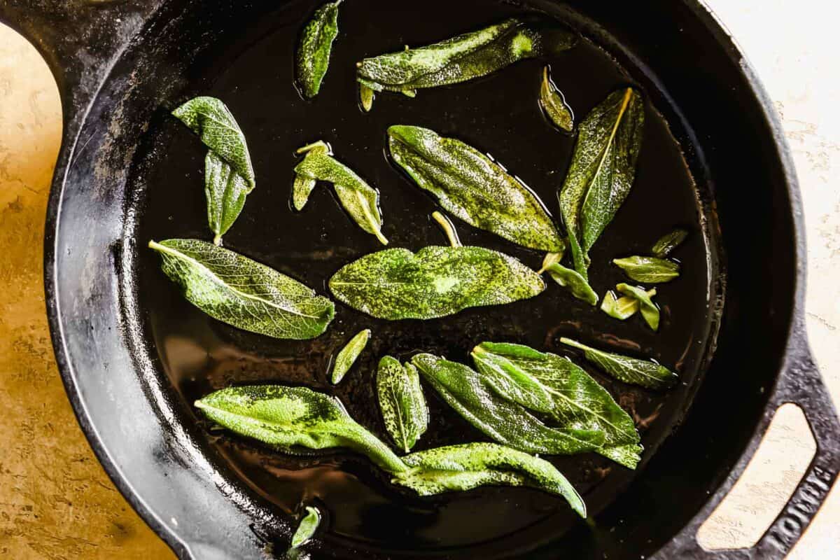fresh sage leaves frying in a cast-iron skillet.