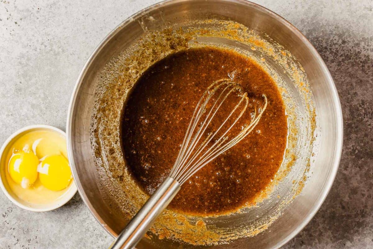 Sugar and browned butter whisked together in a metal bowl.
