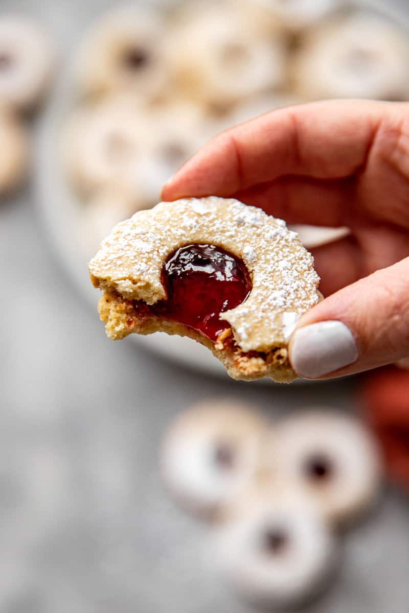 Linzer cookie with a bite taken out of it showing the drippy jelly and tender cookies. 