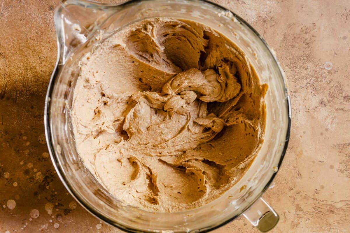 Peanut butter, butter and sugar whipped into a light batter in a glass mixing bowl.
