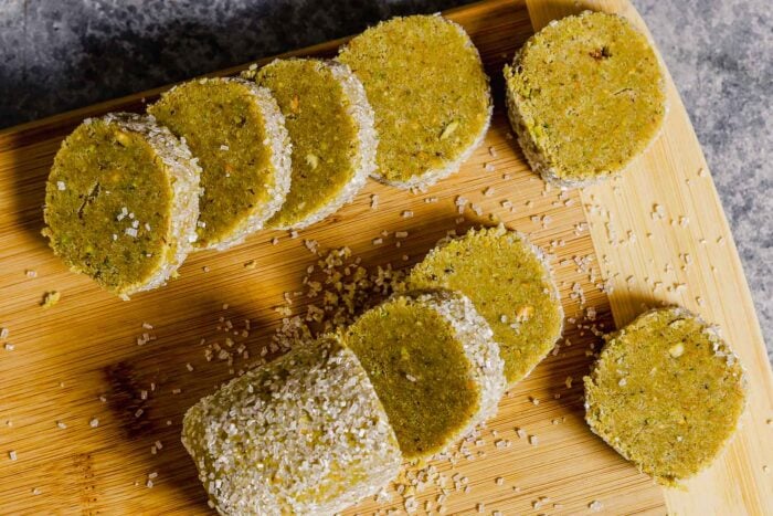 Pistachio shortbread cookie dough log coated in sparkling sugar and sliced into rounds.