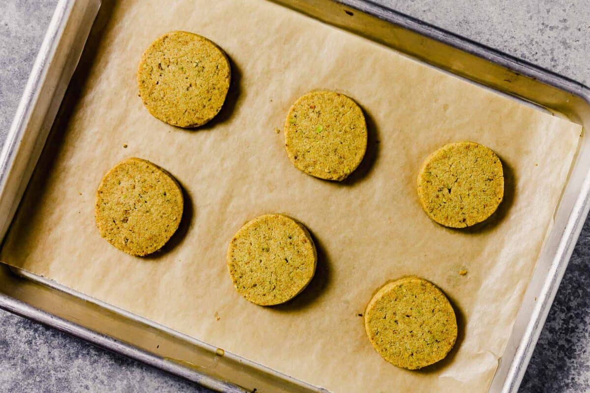 Pistachio shortbread cookies baked and set on a parchment-lined baking sheet.