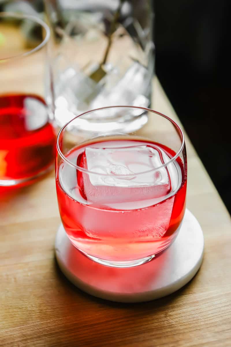 Light pink-colored clarified milk punch cocktail in a rocks glass.