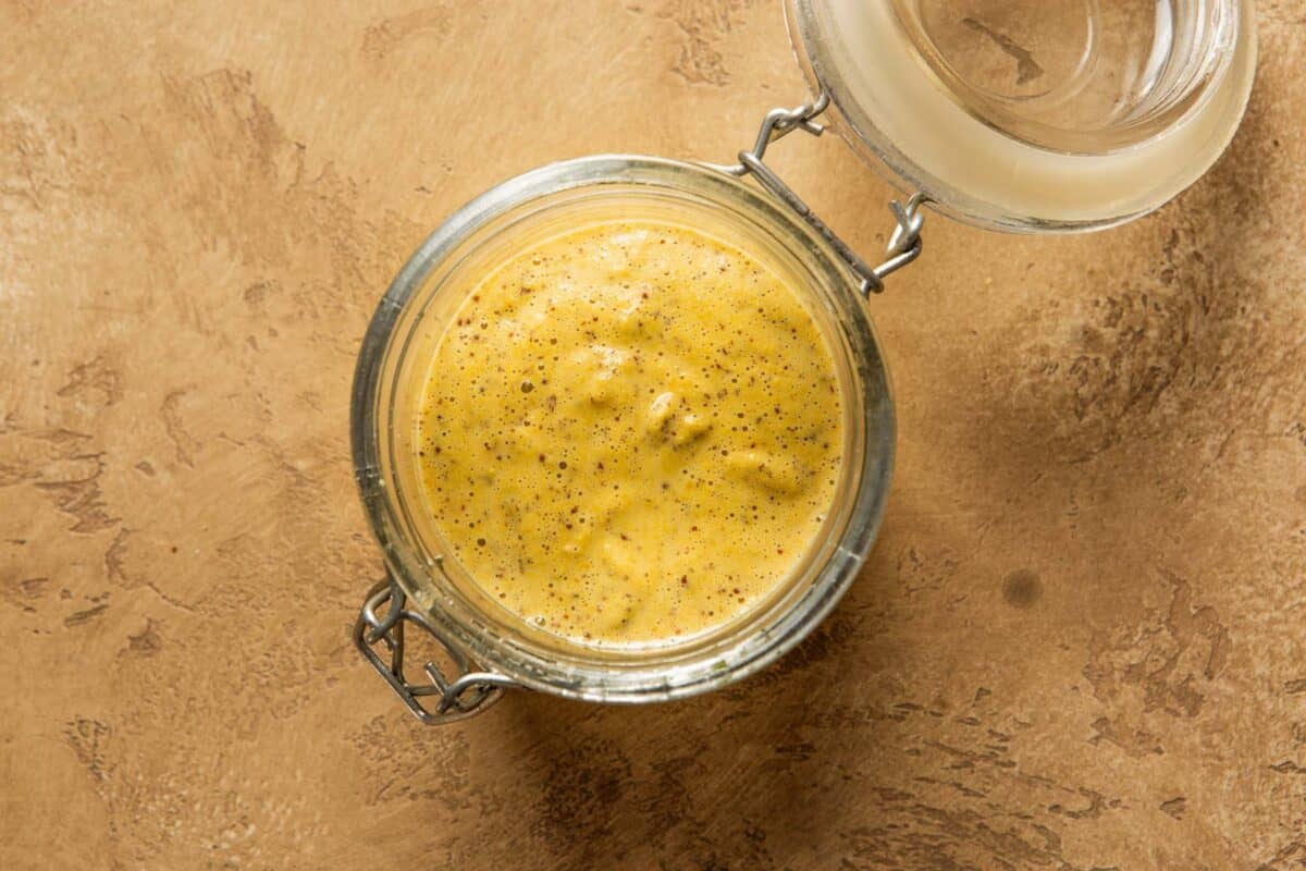 homemade Dijon mustard in a glass container with a lid