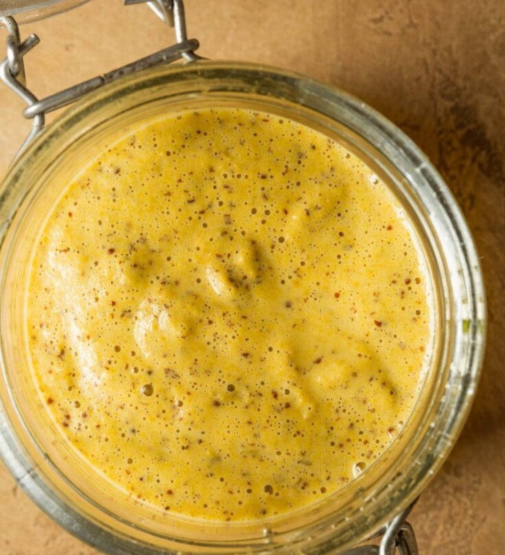 homemade Dijon mustard in a glass container with a lid