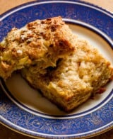 Buttery, flaky cheese biscuit torn in half on a blue-rimmed plate.