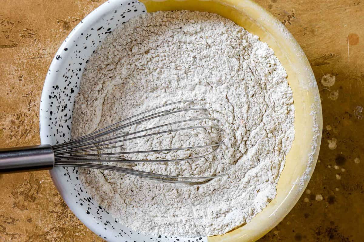 flour, rye flour, and cumin seeds mixed together in an enameled bowl.