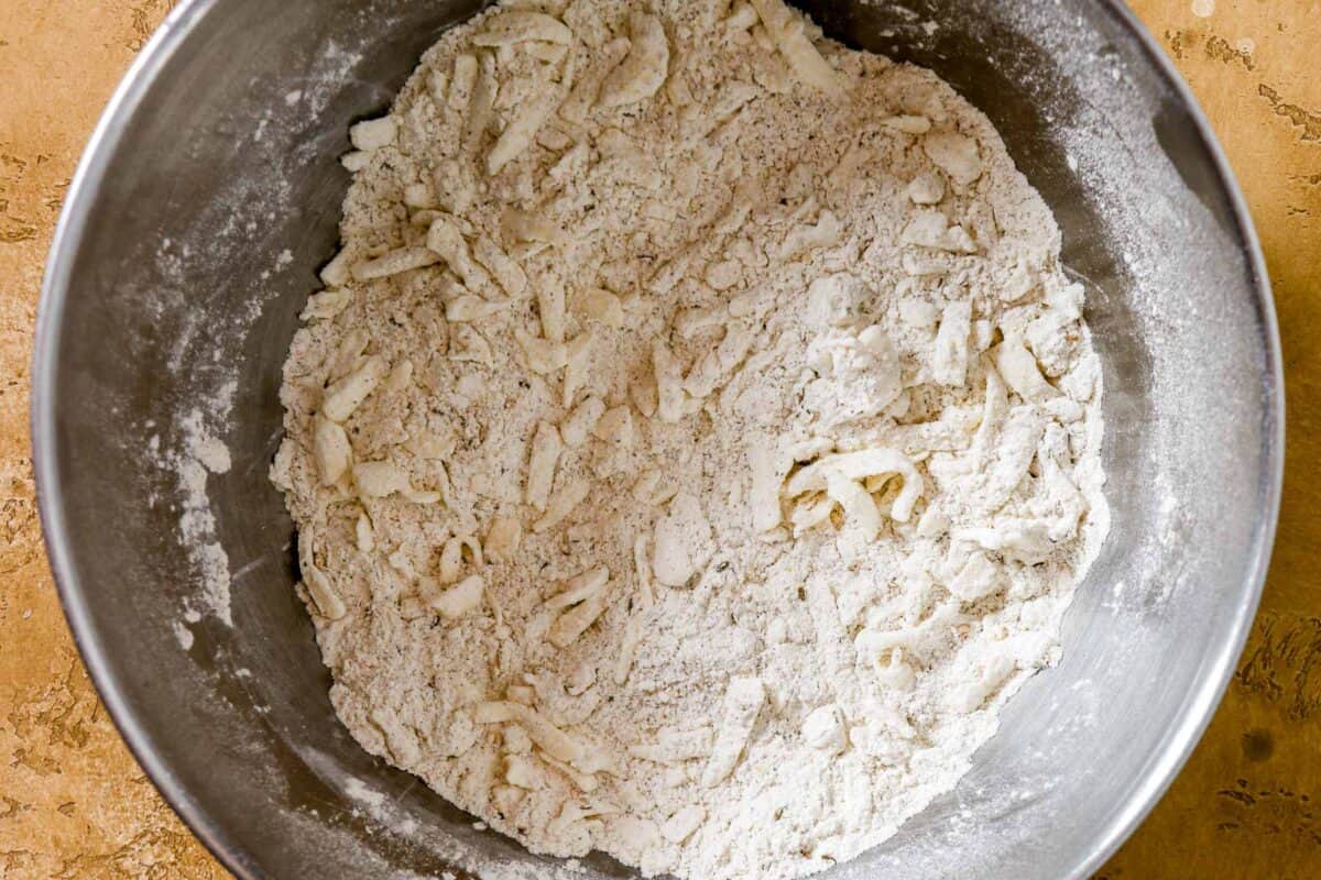 Flour, spices and shreds of butter in a large metal mixing bowl.