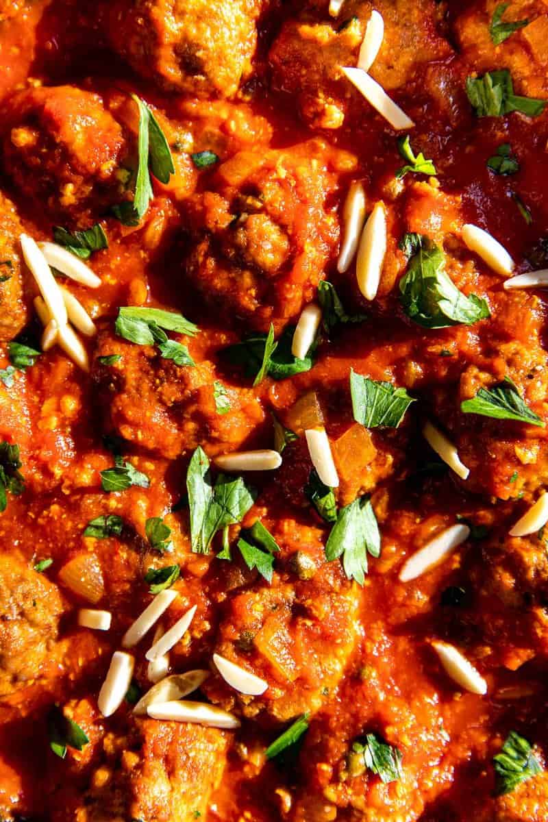 Meatballs in a tomato sauce with slivered almonds and chopped parsley.