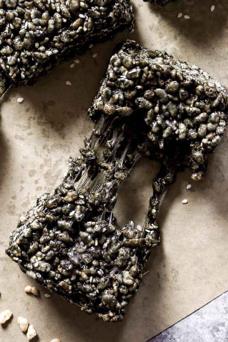 Black sesame rice krispie treat being pulled apart on a counter.