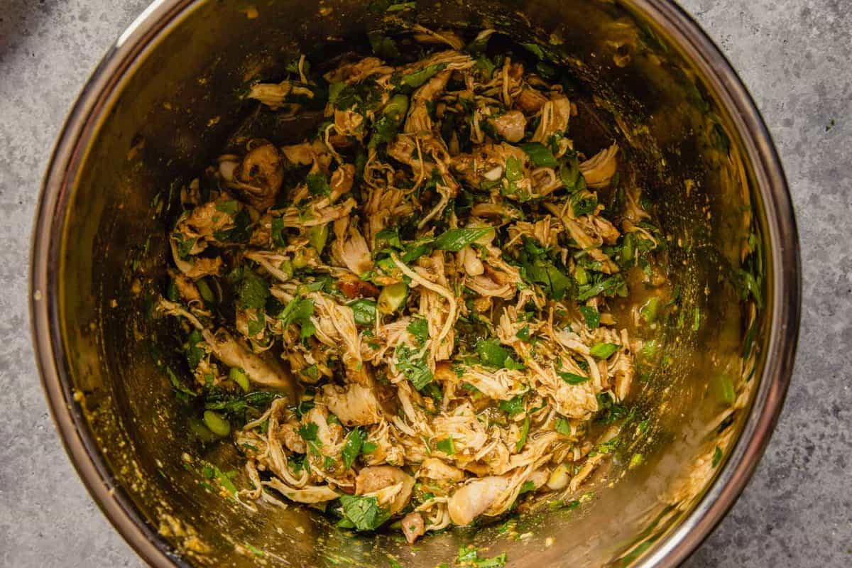 Shredded chicken in salsa verde and herbs in an Instant Pot.