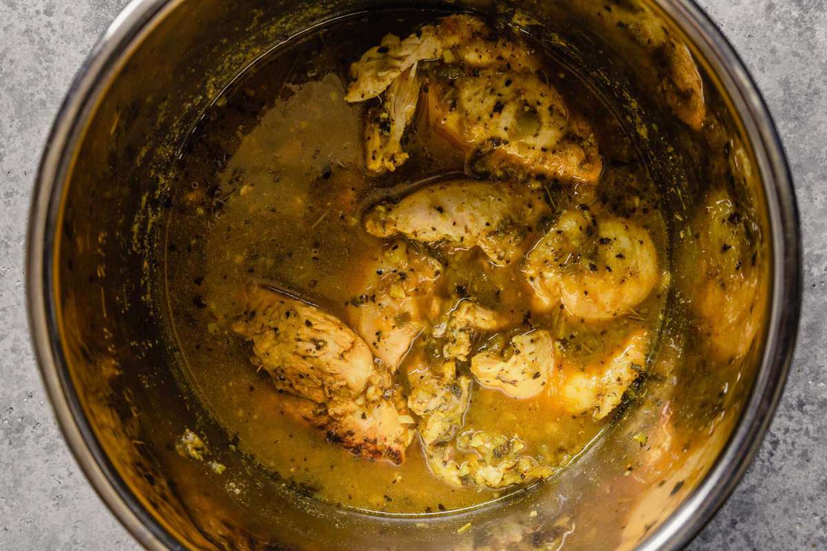 Cooked chicken in salsa verde in a pot.