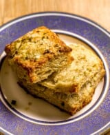 Golden brown buttermilk biscuit separated into two halves set on a blue-rimmed plate.