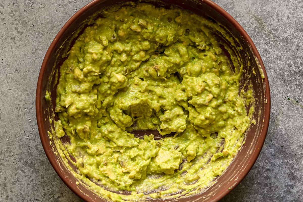 Mashed avocado sauce in a large brown bowl.