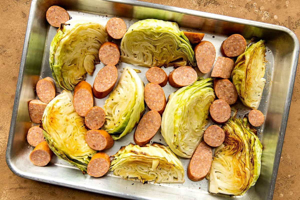 Sliced sausage on a sheetpan with roasted cabbage.