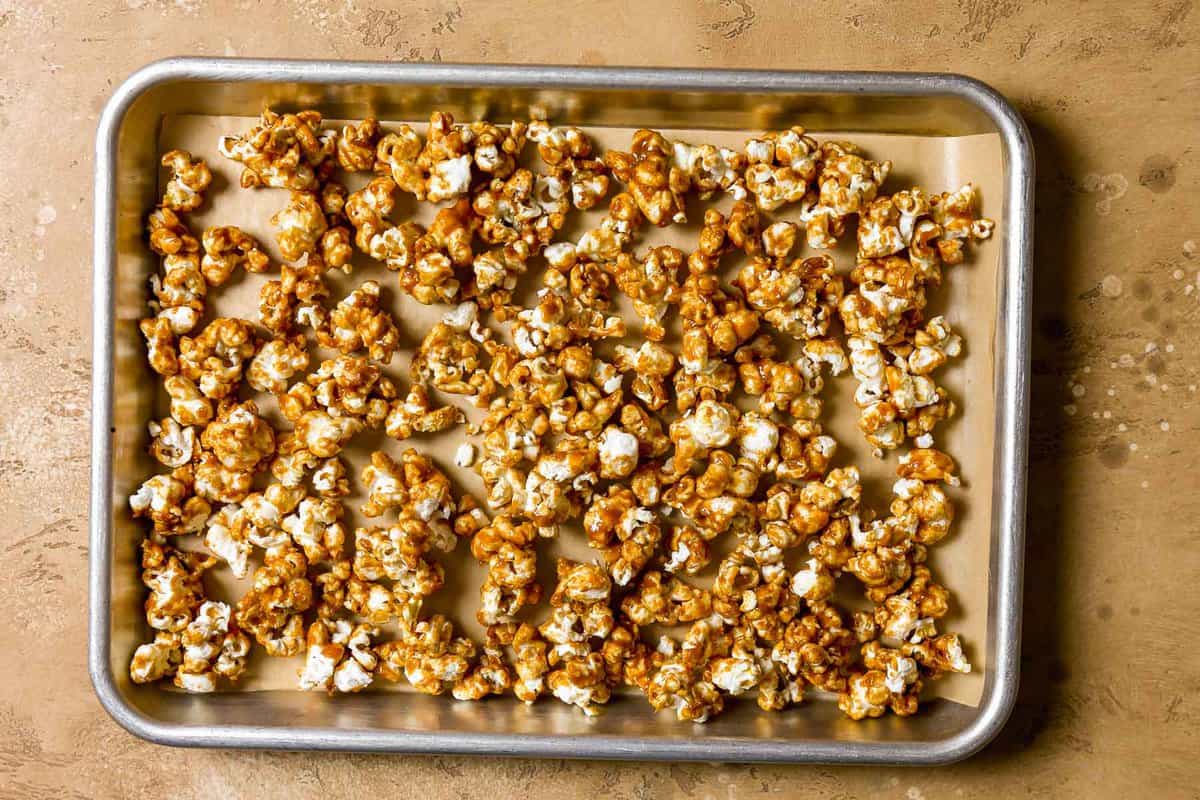 Spicy caramel popcorn on a parchment lined baking sheet.