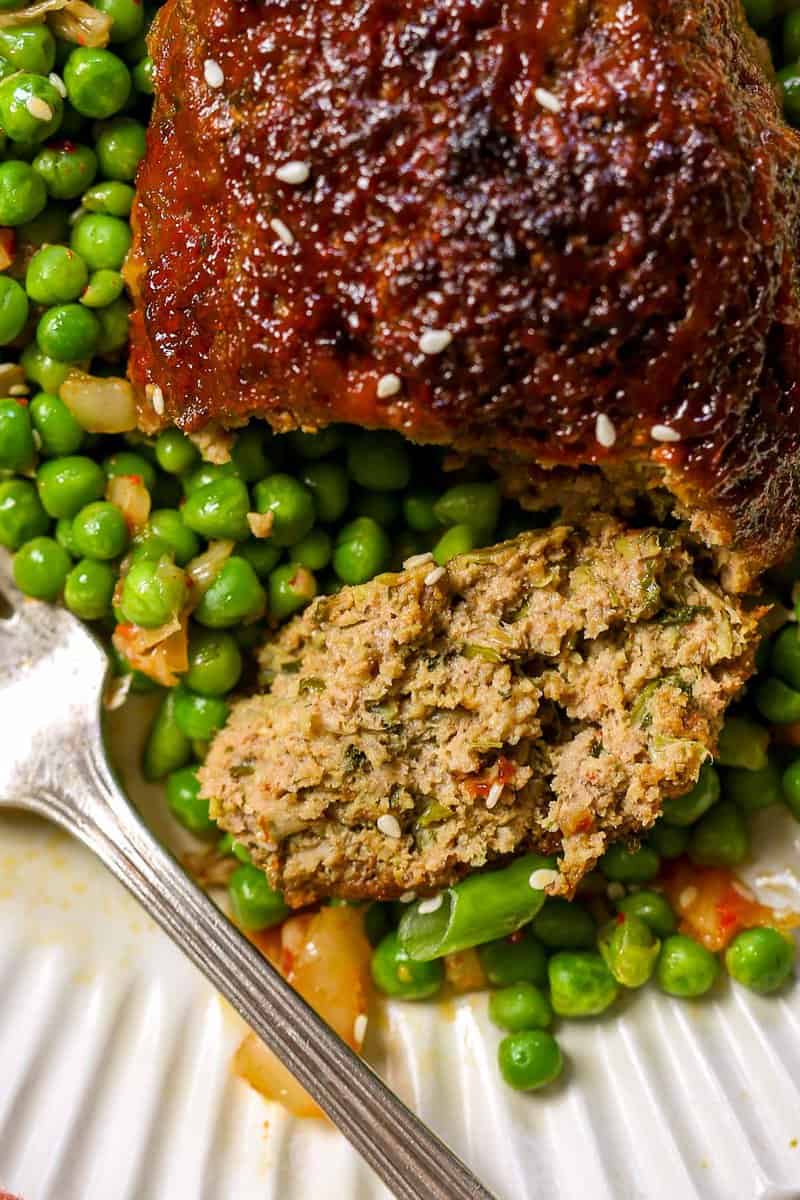 Mini meatloaf cut into on a bed of peas.