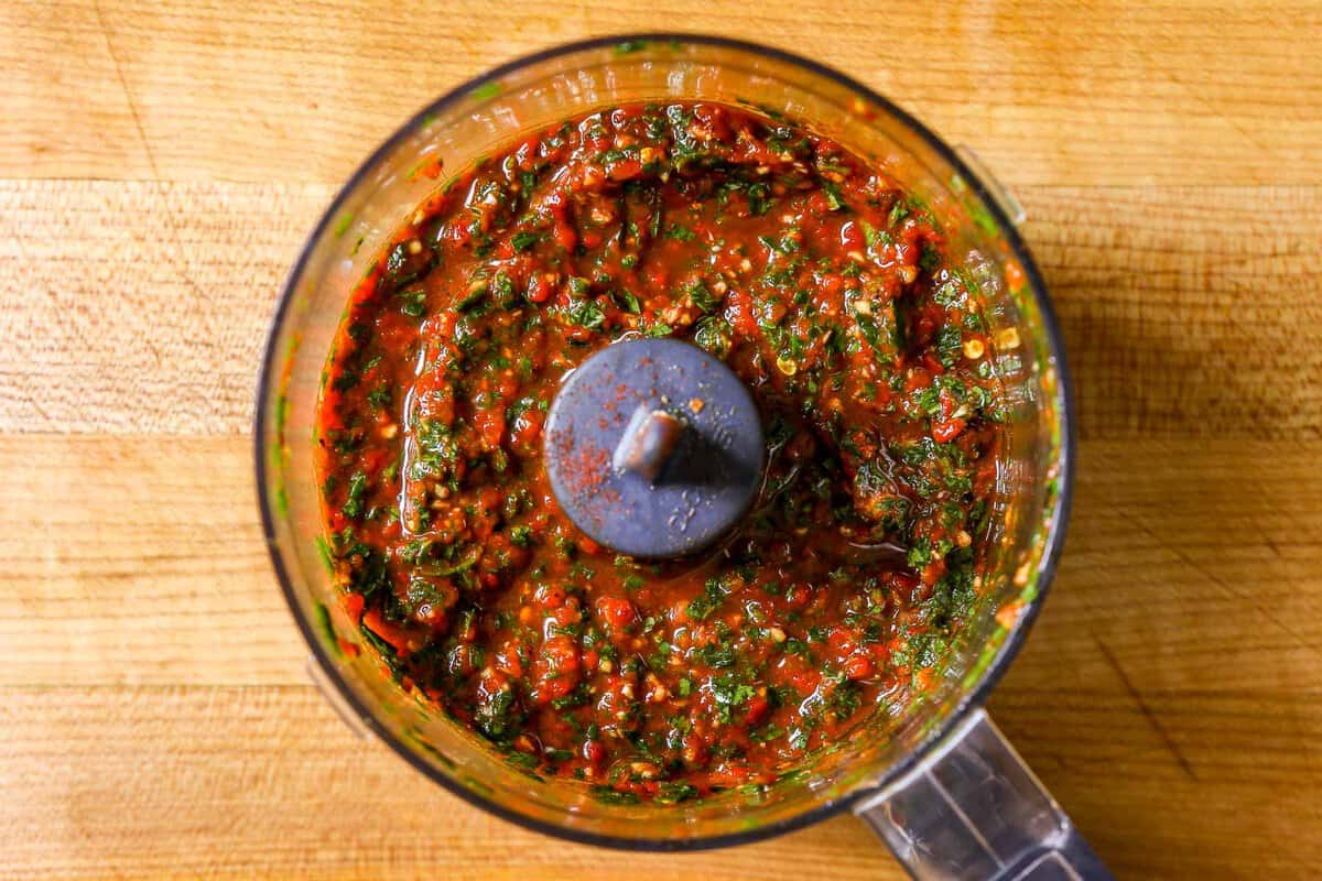 Minced roasted red pepper and herbs in a food processor.