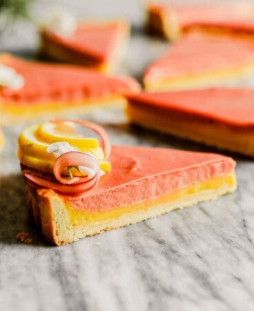 Slice of tart on a marble countertop with a layer of lemon filling and a layer of rhubarb filling.
