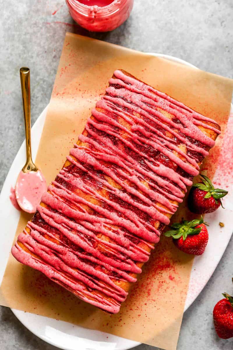 Strawberry pound cake on a parchment-lined platter with strawberries set around. 