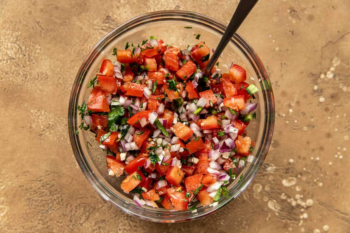 Fresh pico de gallo—diced tomatoes, onions, cilantro, jalapeno and garlic—in a glass mixing bowl.