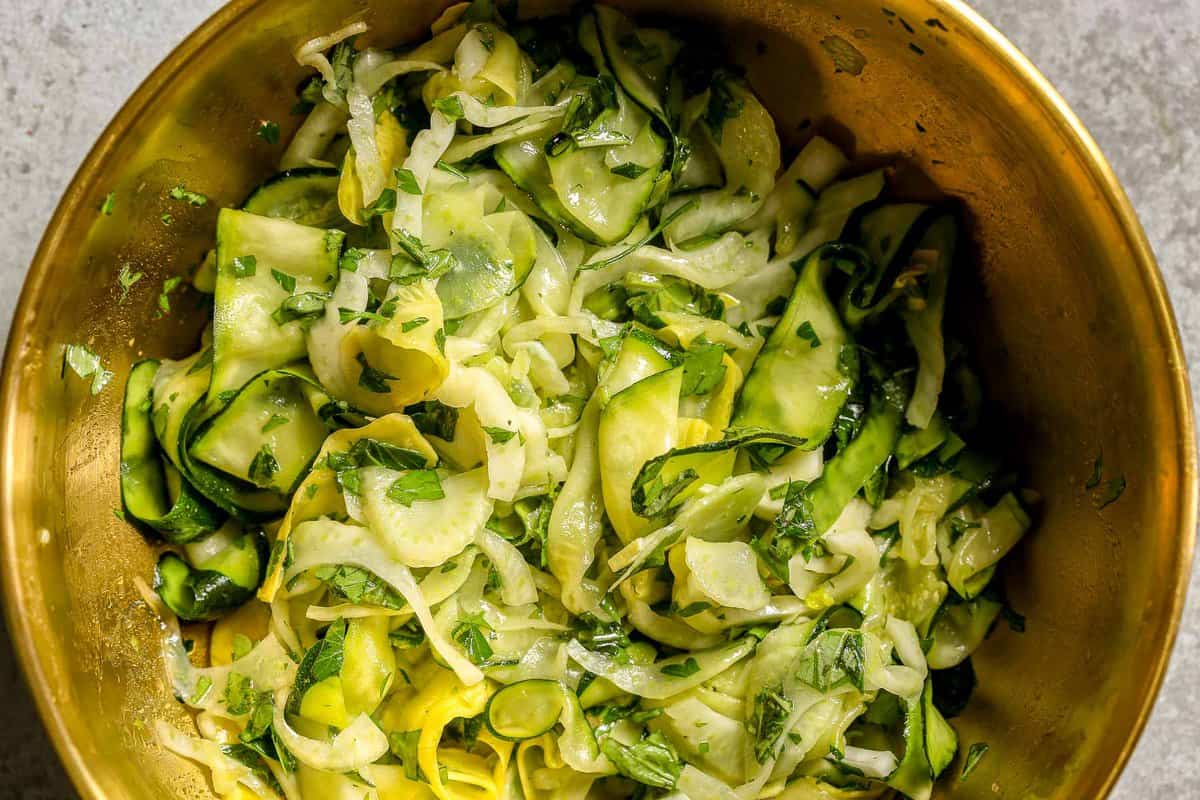 Ribboned zucchini and summer squash salad in a large gold mixing bowl.