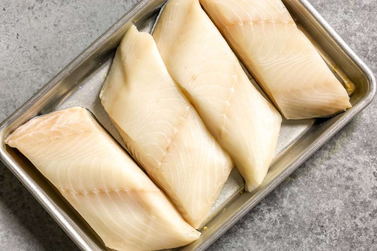 Sablefish fillets on a metal baking sheet.