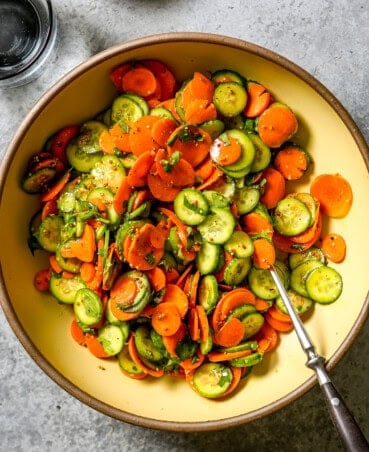 Thinly sliced carrots and cucumbers and coated in a mustard vinaigrette and tossed with fresh herbs in a large serving bowl.