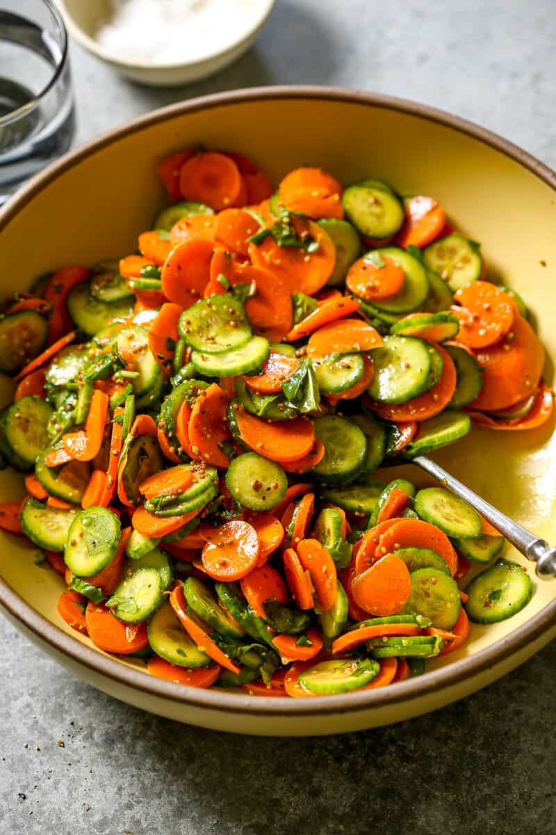 Thinly sliced carrots and cucumbers and coated in a mustard vinaigrette and tossed with fresh herbs in a large serving bowl.