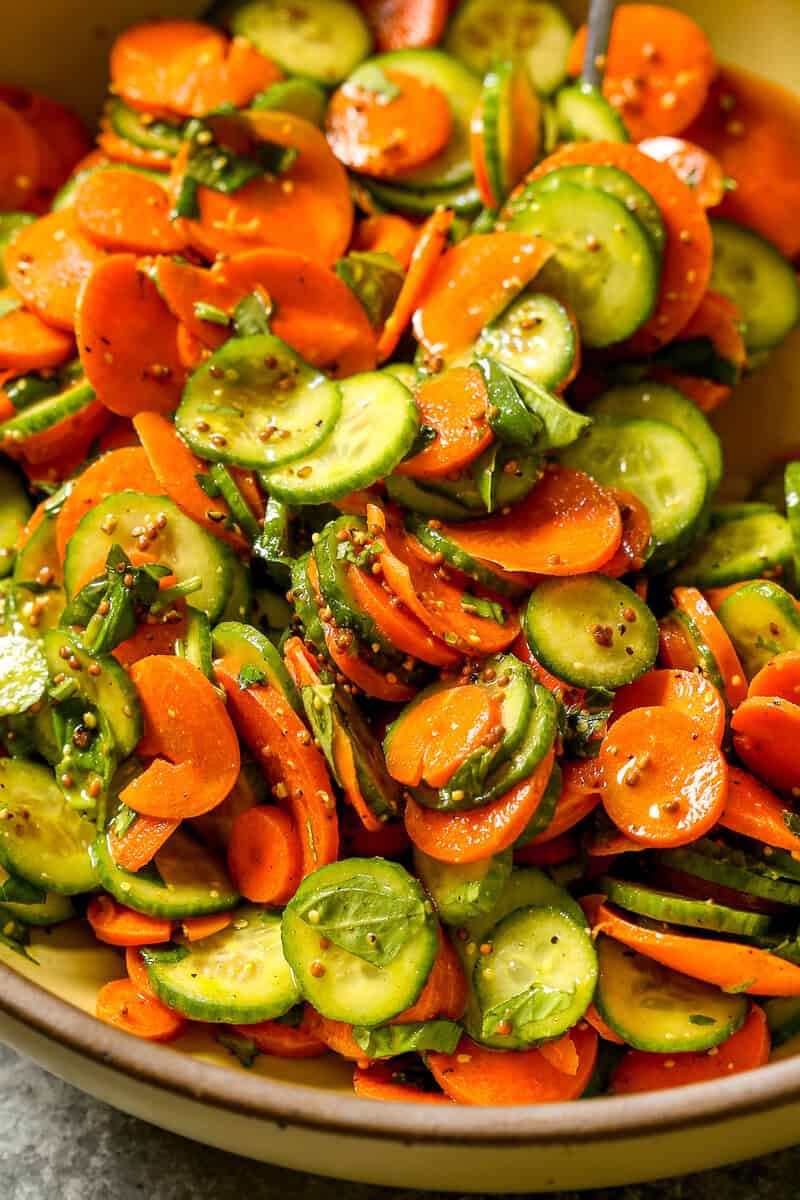 Thinly sliced carrots and cucumbers and coated in a mustard vinaigrette and tossed with fresh herbs in a large serving bowl.