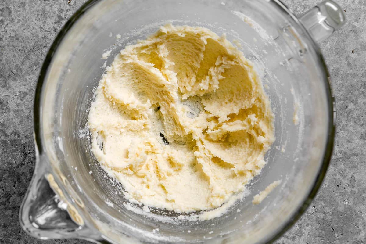 Butter and sugar creamed together in a glass mixing bowl.