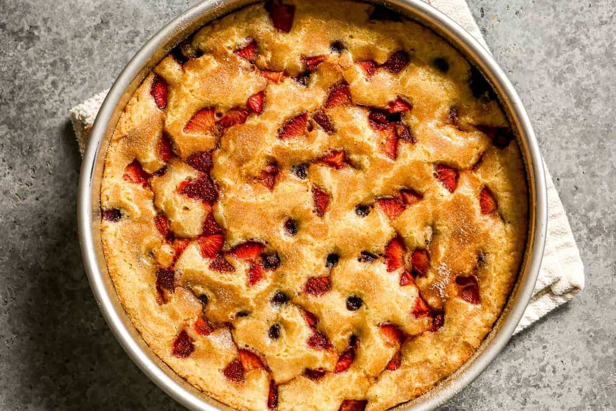 Berry cake in a round baking pan set on a counter.