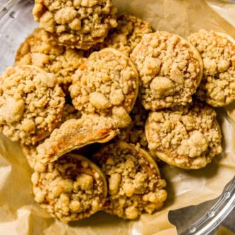 Pumpkin pie cookie set on a stack of pumpkin pie cookies with a bite taken out of the cookie.