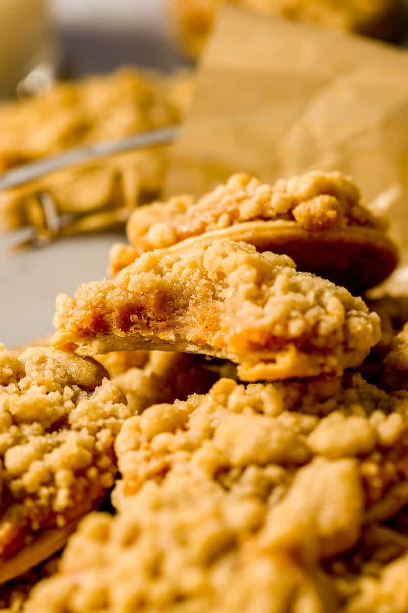 Pumpkin pie cookie set on a stack of pumpkin pie cookies with a bite taken out of the cookie.