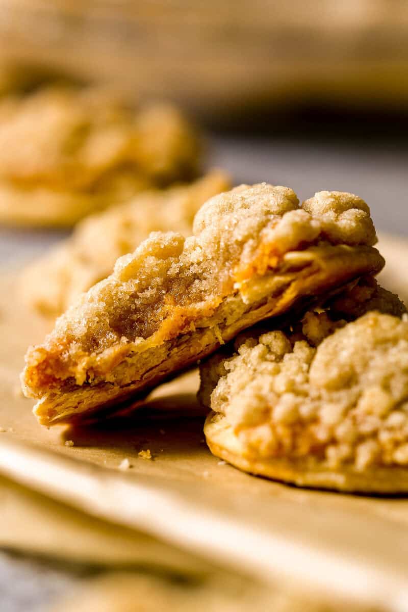 Pumpkin pie cookie, with streusel on top, set on a piece of brown parchment paper, with a bite taken out of the cookie.