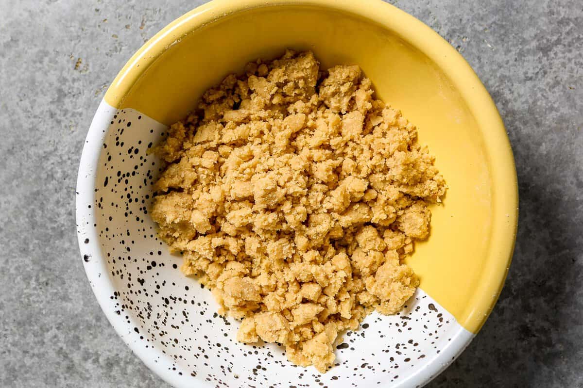 Streusel topping in a yellow, white and black speckled metal bowl.