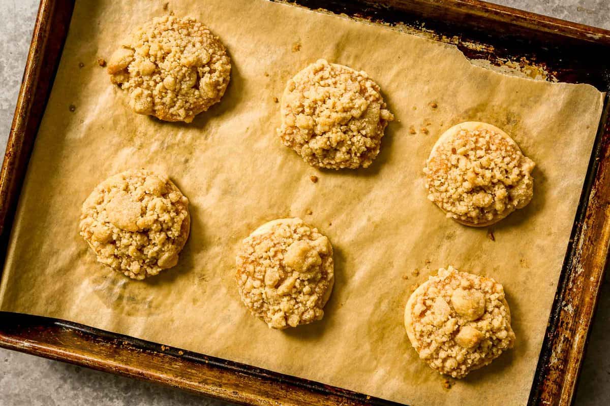 Baked streusel-topped cookies on a parchment-lined baking sheet.