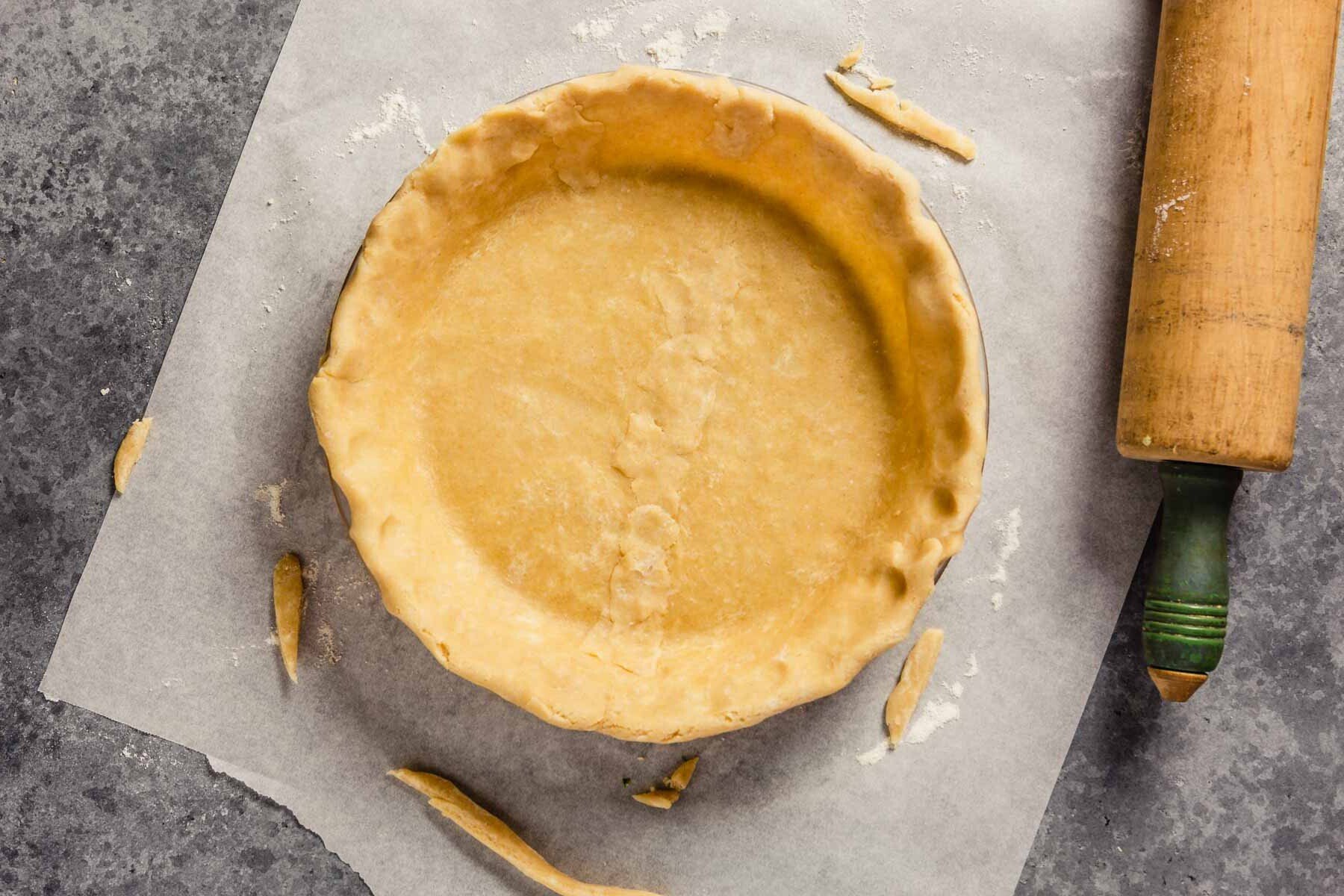 Pie plate lined with unbaked pie crust, set on a counter. 