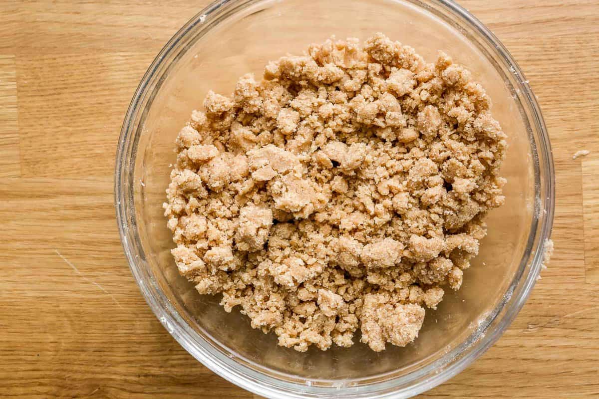 Streusel mixture in a clear glass bowl set on a wood counter.