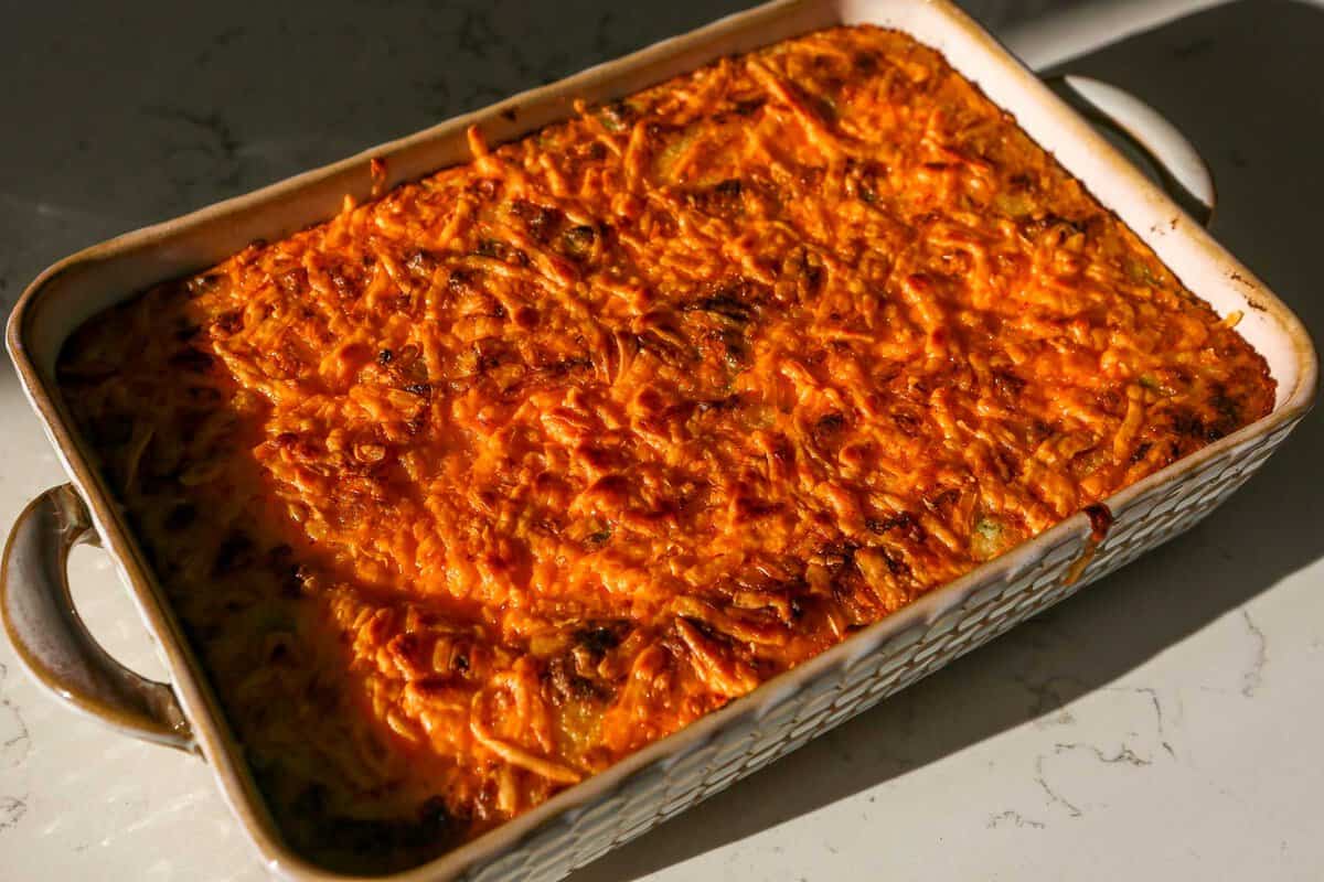 Cheesy potato casserole set on a marble counter top.