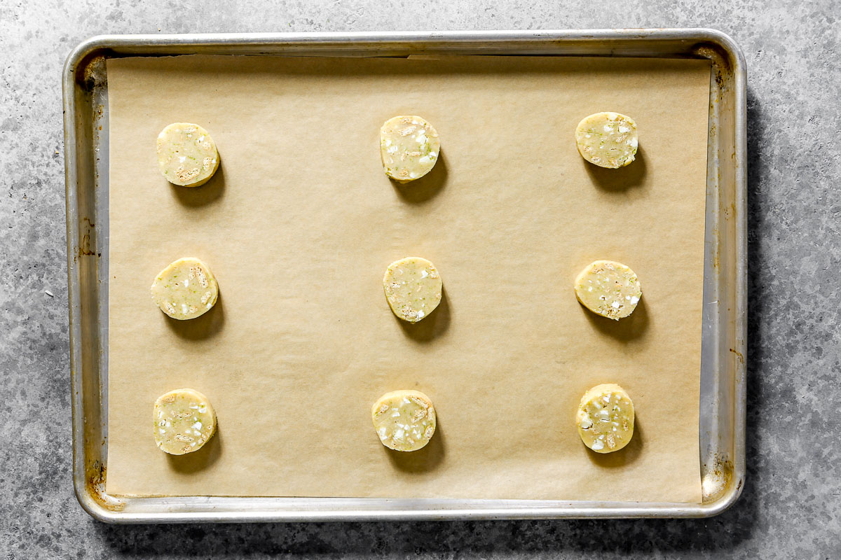 Slices of cookie dough arranged on a parchment lined baking sheet.